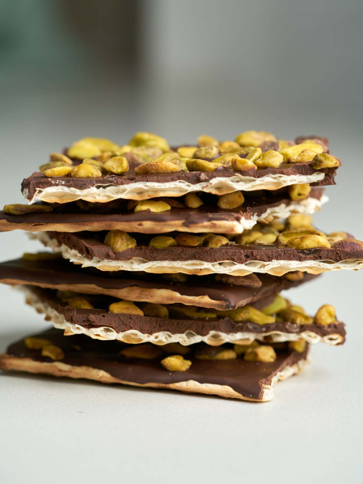 A stack of square pieces of matzo with chocolate and pistachios.