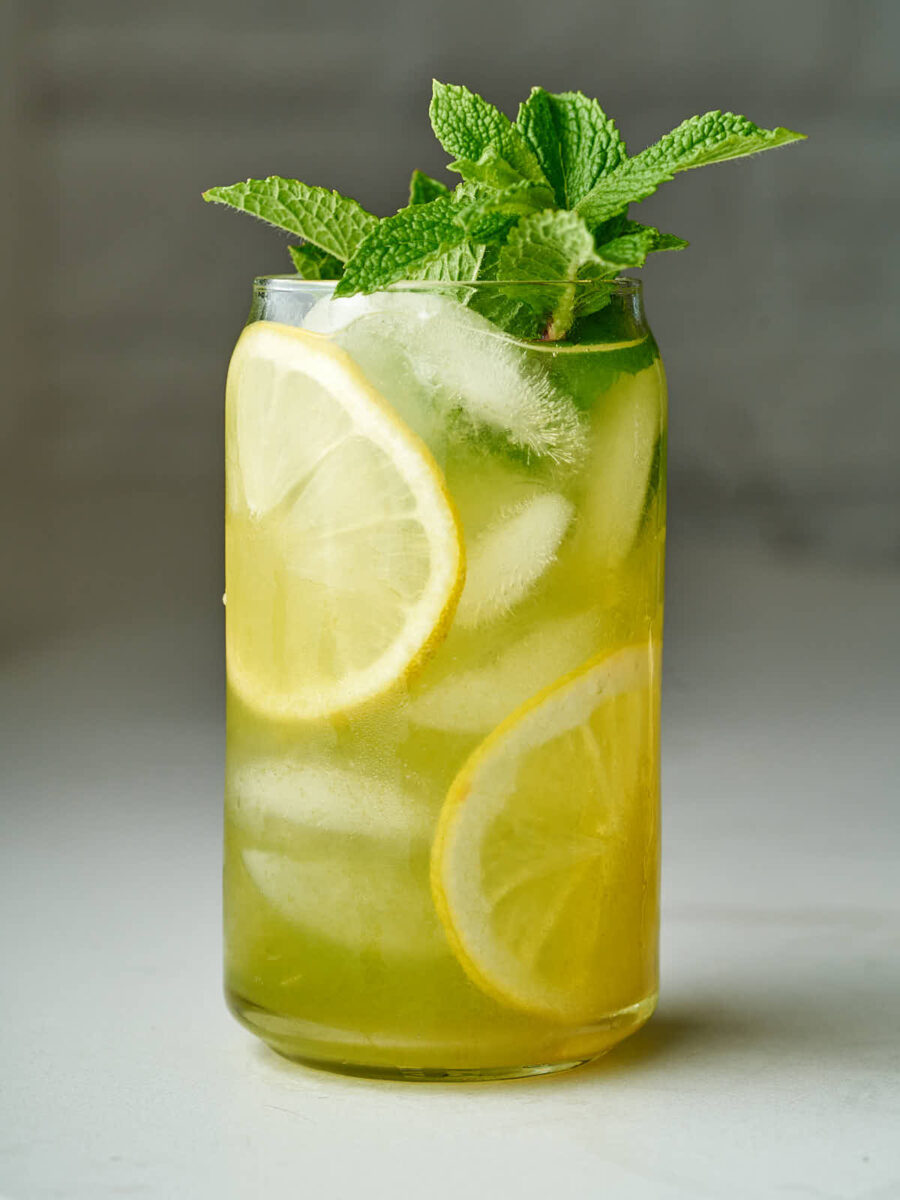 Lemonade in a beer can glass with lemon slices and fresh mint.