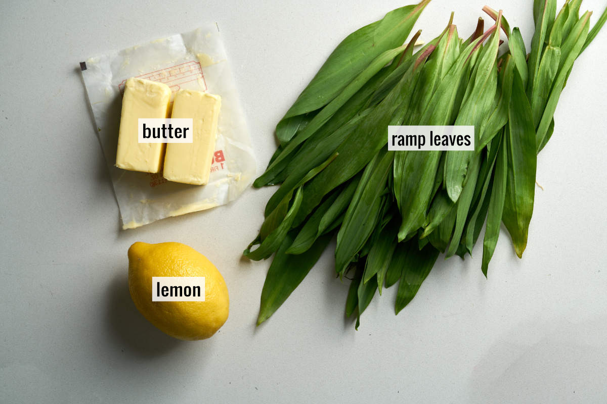 A pile of ramp leaves next to two sticks of butter and a lemon.