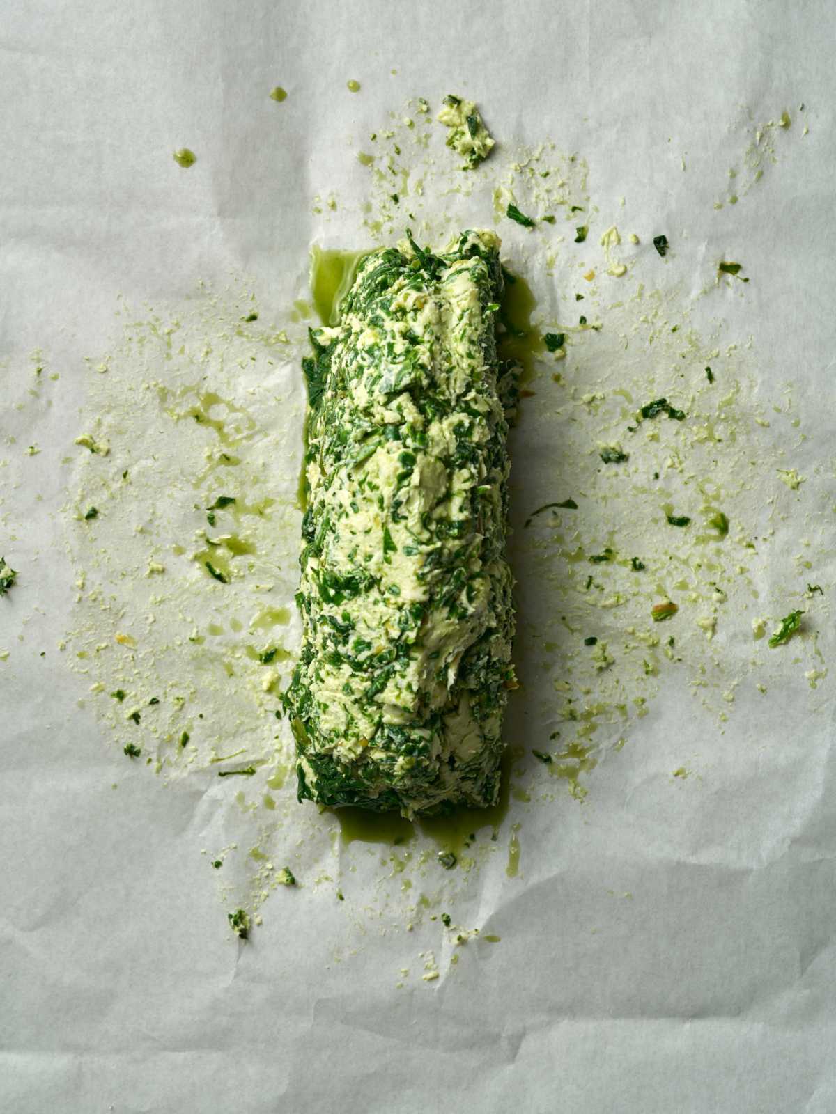 A log of green and beige butter on top of parchment paper