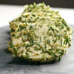 Large circles of green and beige butter on a cutting board