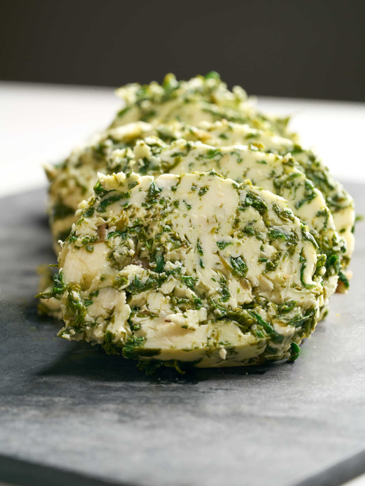 Large circles of green and beige butter on a cutting board