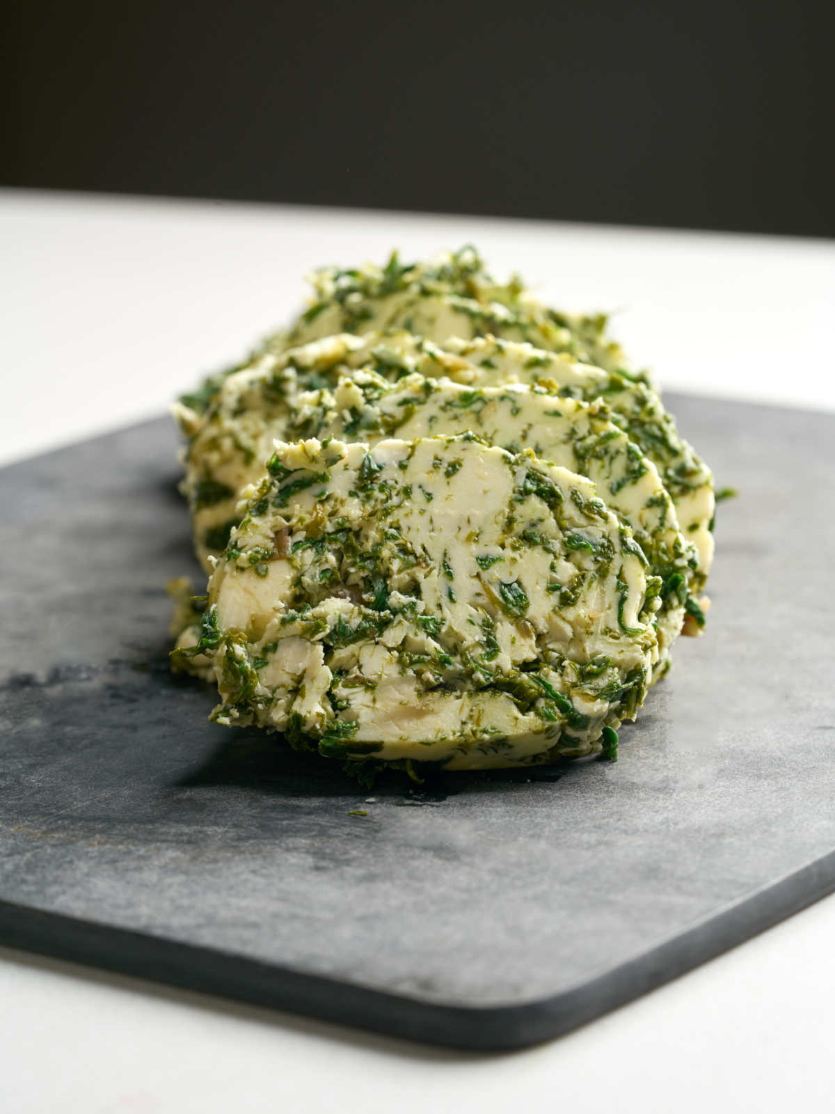 Large circles of green and beige butter on a cutting board