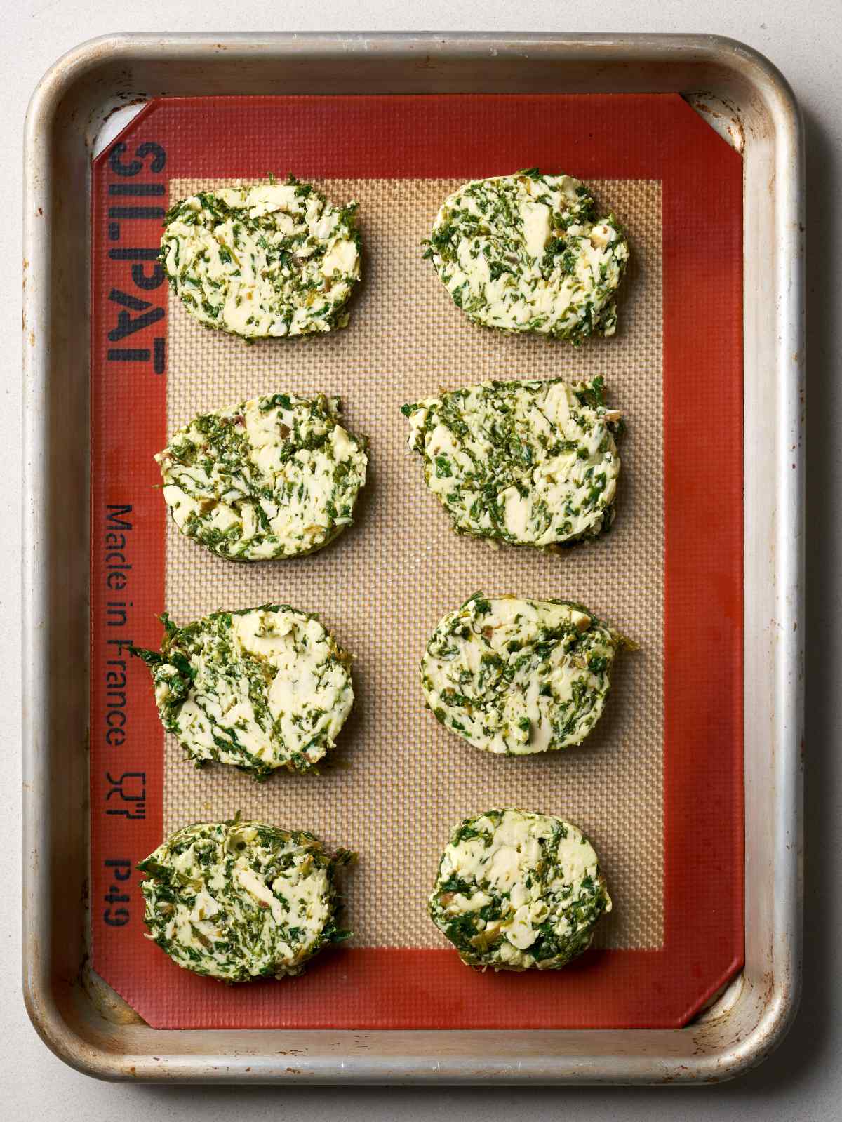 Eight compact circles of butter on a baking sheet