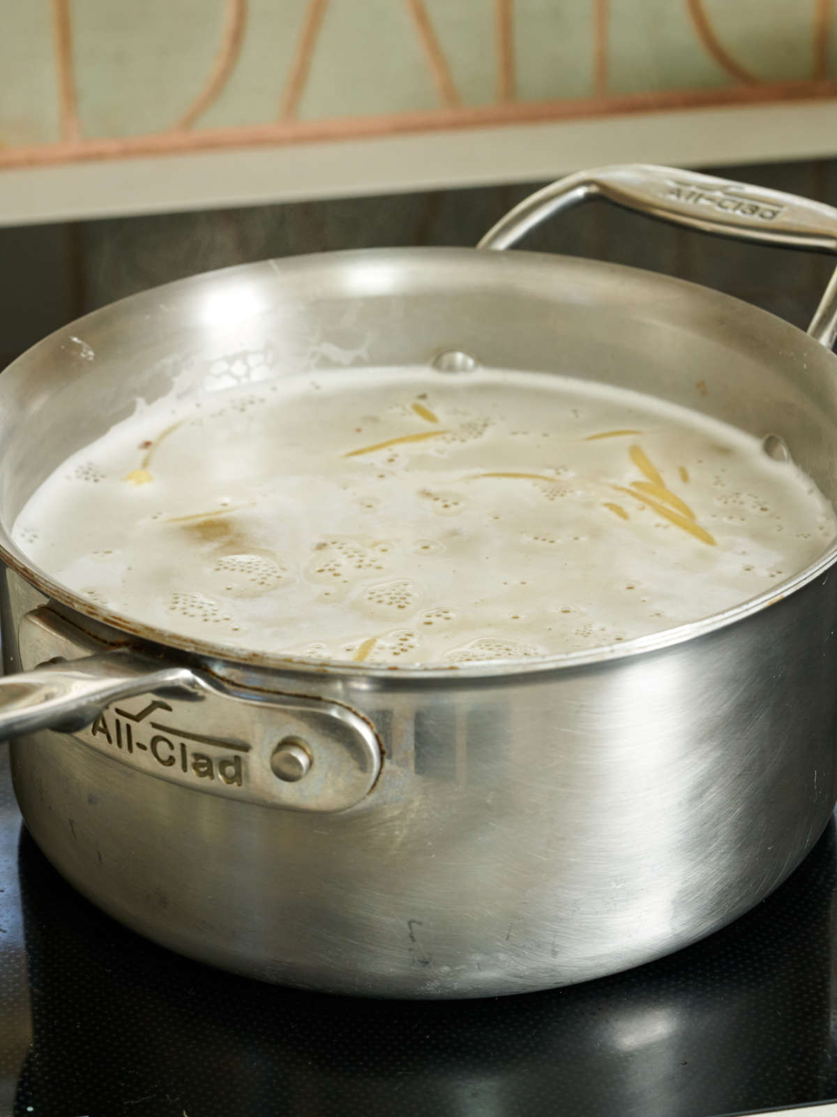 Pasta noodles in boiling hot water in a large silver saucepan