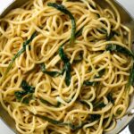 Cooked bucatini pasta with greens in a large silver sauce pan