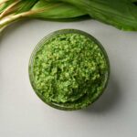 Top down view of a jar of vibrant green pesto