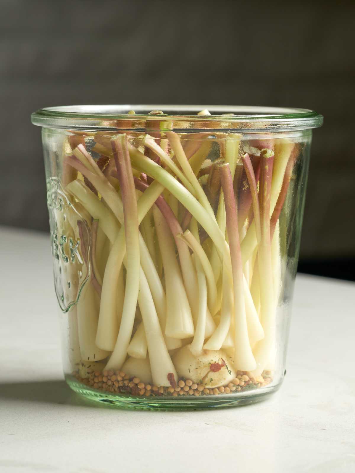 White ramp bulbs with herbs and spices in an open glass jar