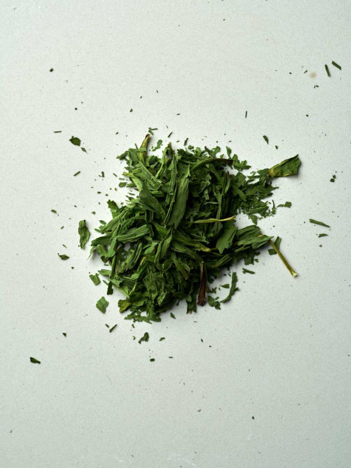 Dried and crumbled green leaves in a pile