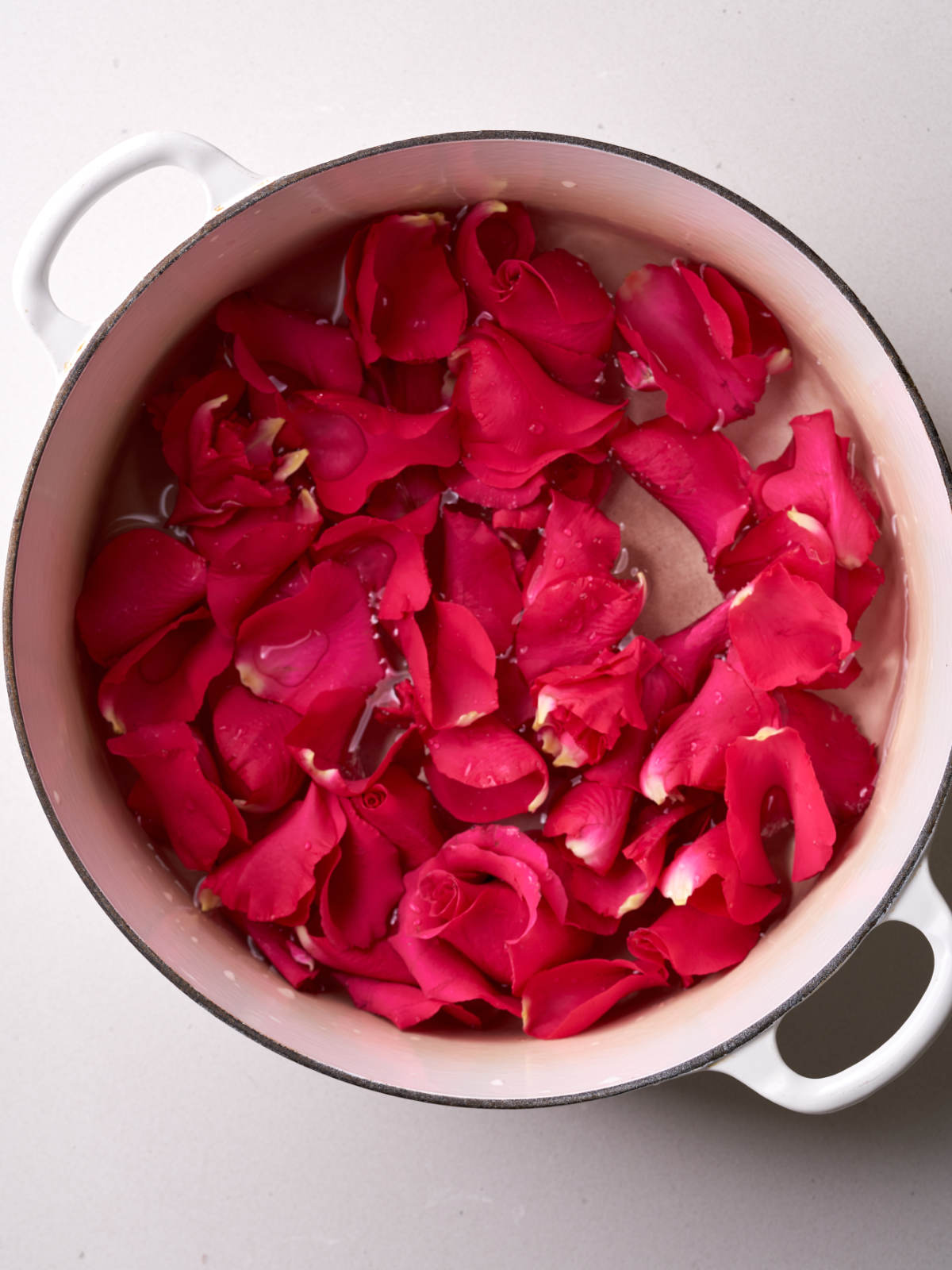 White pot filled with rose petals and water.