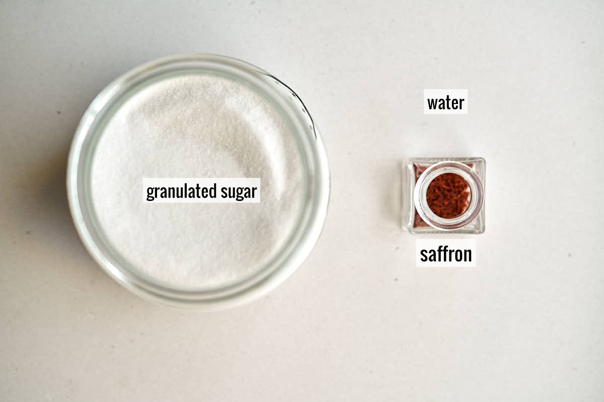 A container of white sugar next to a small jar of saffron threads.