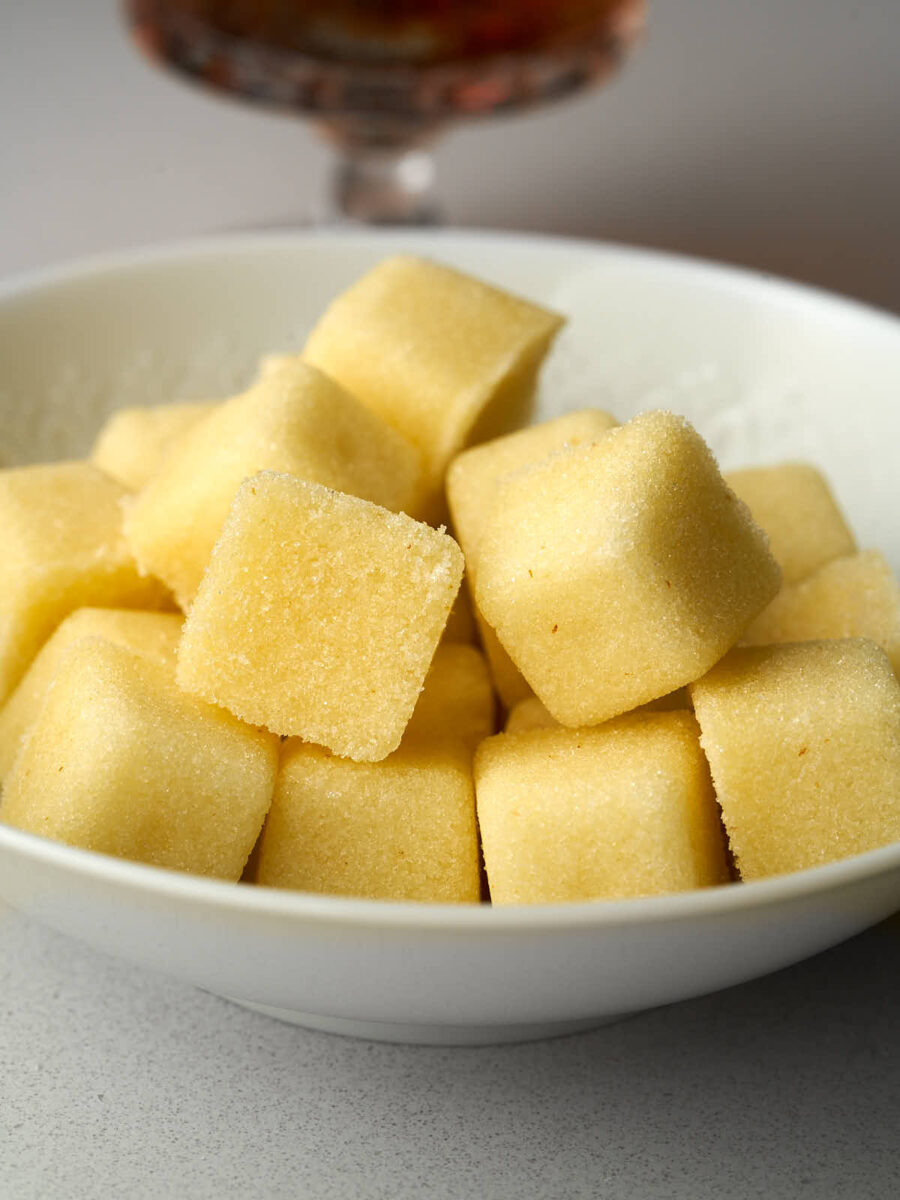 Yellow sugar cubes in a white bowl.