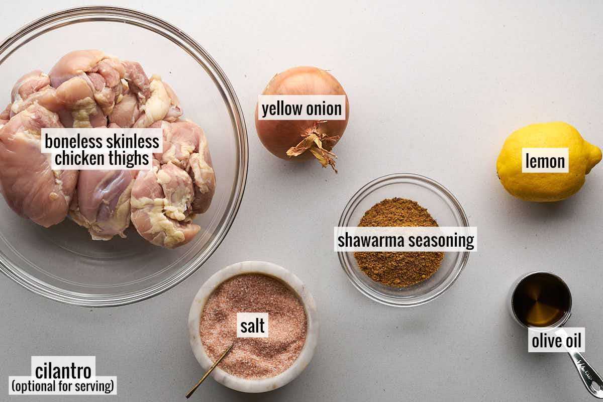 Ingredients for chicken shawarma including chicken thighs, onion, lemon, and seasonings.