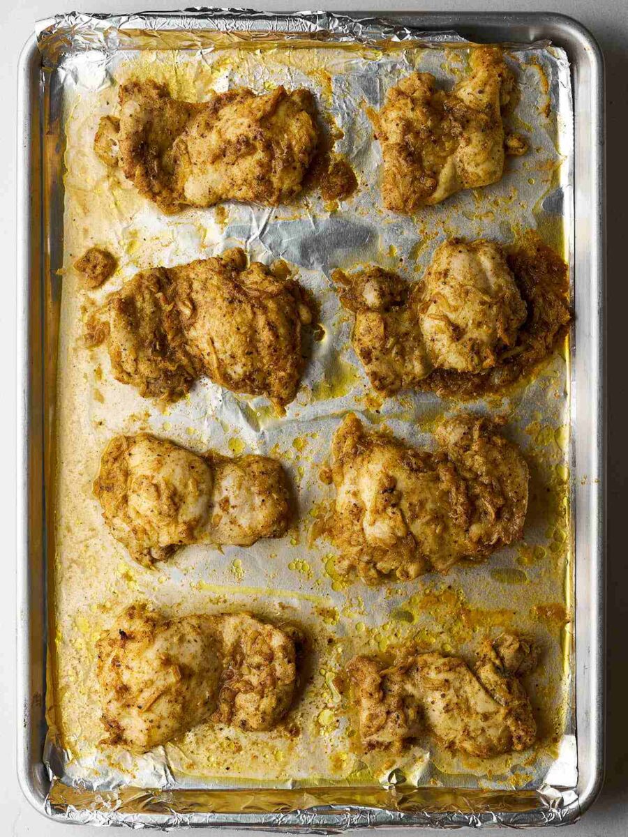 Cooked chicken thighs laid out on a sheet pan with metal foil.