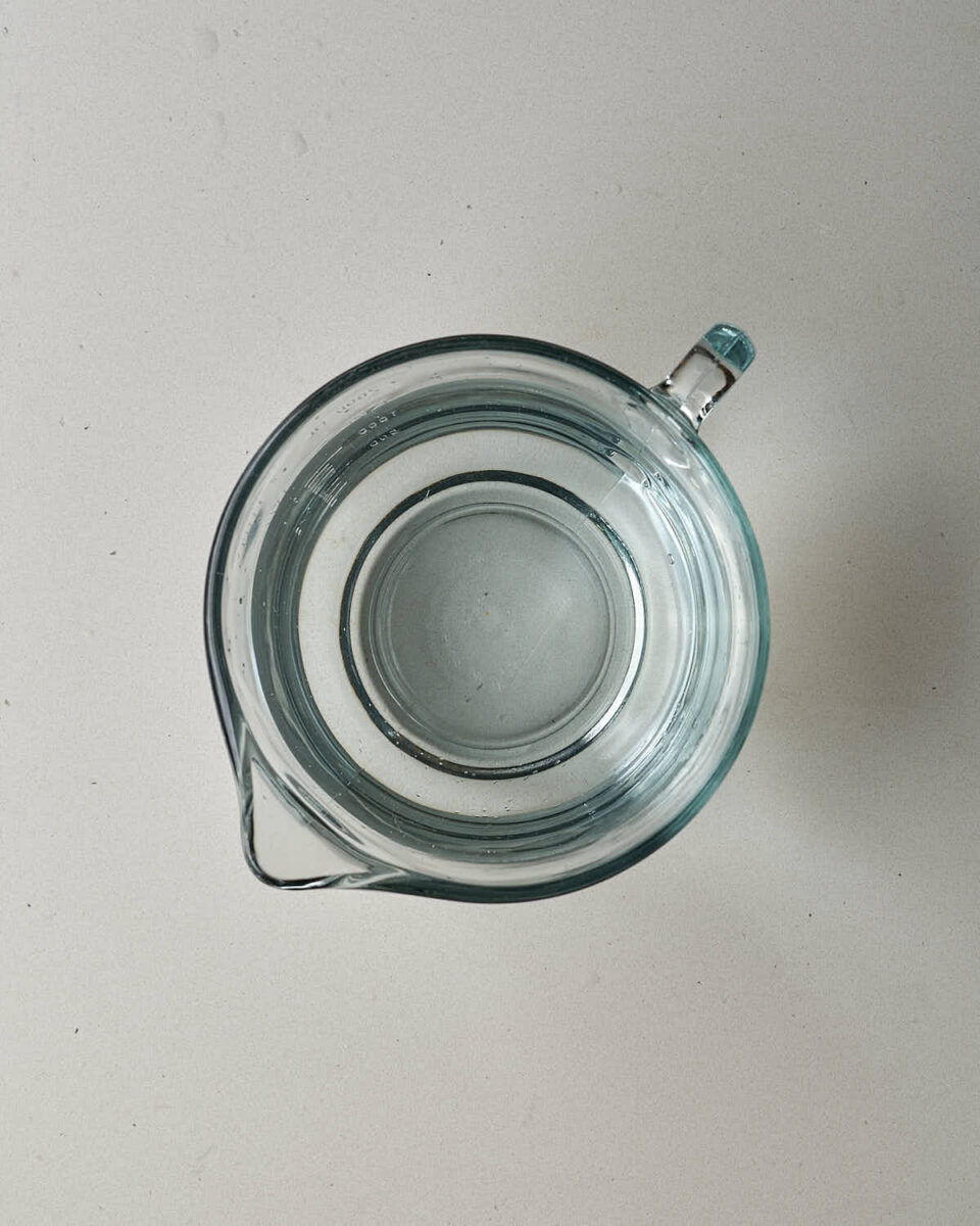 An overhead view of a clear glass measuring cup filled with water.