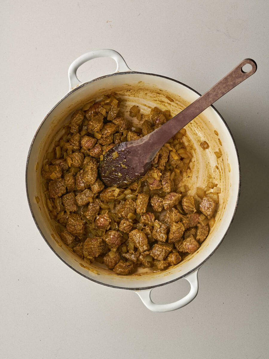 Cubed meat and turmeric added to the sautéed onions in the pot.