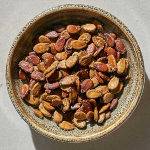 Roasted watermelon seeds in a small dish on a countertop.