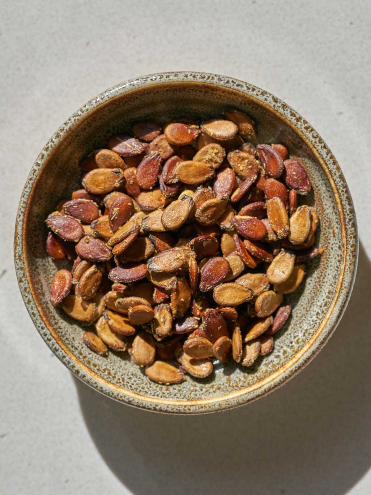 Roasted watermelon seeds in a small dish on a countertop.